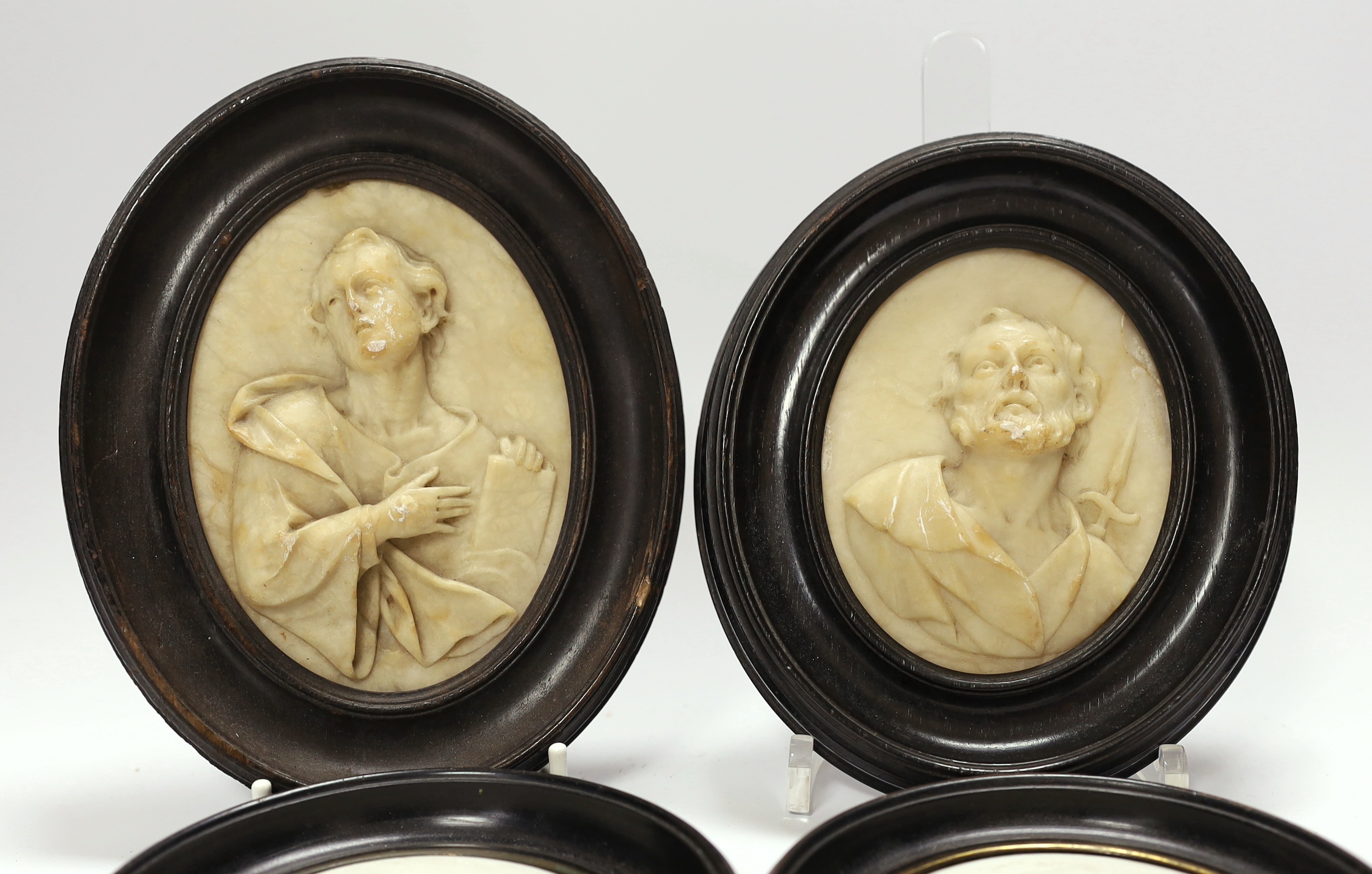 A pair of 19th century alabaster relief carved religious plaques and a pair of Sevres biscuit porcelain portrait plaques of Louis Napoleon and Eugene, housed in ebonized frames, largest overall 16cm high